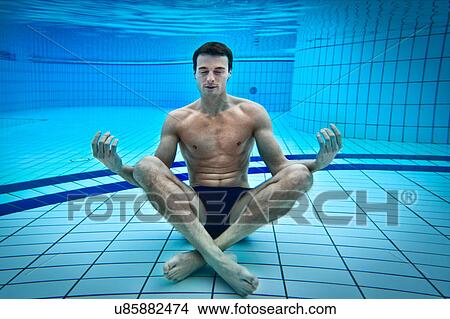 Picture - Man meditating in swimming pool. Fotosearch