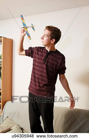 Stock Photo - Man playing with toy airplane on couch. Fotosearch