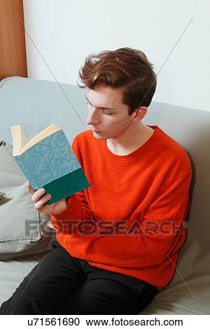 Stock Image - Man reading book on couch. Fotosearch
