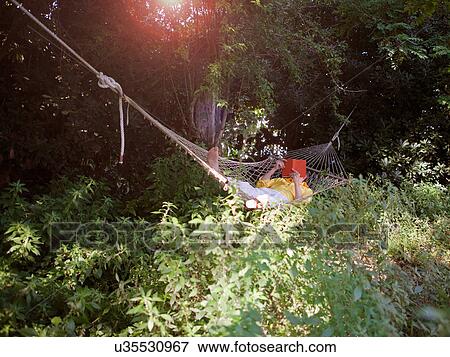 Stock Photo - Man reading in hammock outdoors. Fotosearch