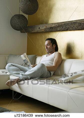 Man reading newspaper on couch View Large Photo Image Stock Photo - Man reading newspaper on couch. Fotosearch