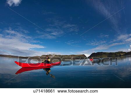 Stock Image - Man rowing canoe in still lake. Fotosearch
