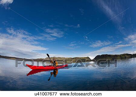 Stock Photo - Man rowing canoe in still lake. Fotosearch