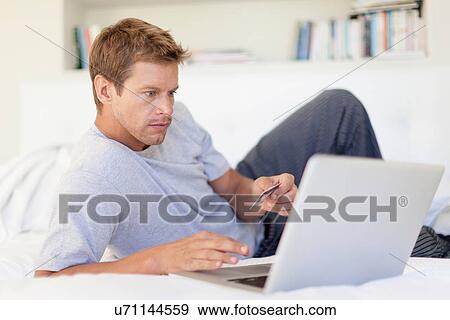 Stock Photo - Man shopping online with laptop. Fotosearch