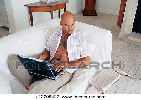 Man studying with laptop on couch View Large Photo Image Stock Image - Man studying with laptop on couch. Fotosearch