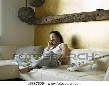 Man talking on cell phone on couch View Large Photo Image Picture - Man talking on cell phone on couch. Fotosearch