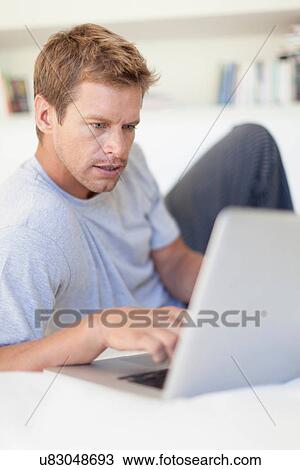 Stock Image - Man using laptop in bed. Fotosearch