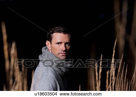 Picture - Man walking in wheat field at night. Fotosearch