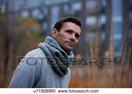 Stock Image - Man wearing knitted scarf outdoors. Fotosearch