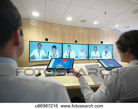 Medical professionals in meeting room using screens in video conference View Large Photo Image Stock Photograph - Medical professionals in meeting room using screens in video conference. Fotosearch