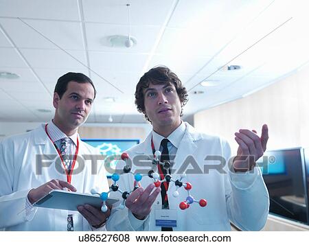 Stock Photo - Molecular scientist and apprentice holding molecular model and digital tablet. Fotosearch