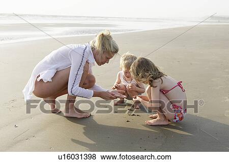 Stock Photo - Mother and children playing on beach. Fotosearch