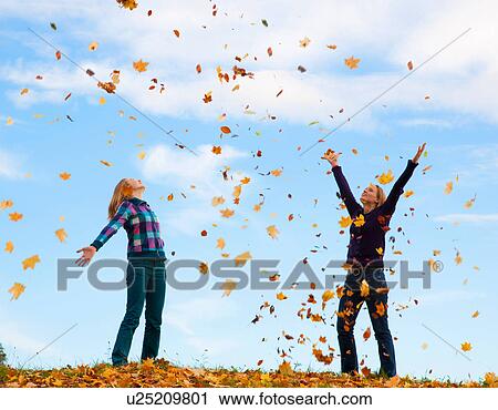 Stock Image - Mother and daughter playing in leaves. Fotosearch