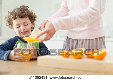 Mother pouring orange juice for son View Large Photo Image Stock Image - Mother pouring orange juice for son. Fotosearch