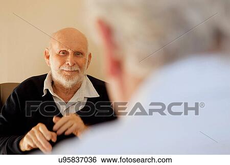 Stock Photograph - Older men talking indoors. Fotosearch
