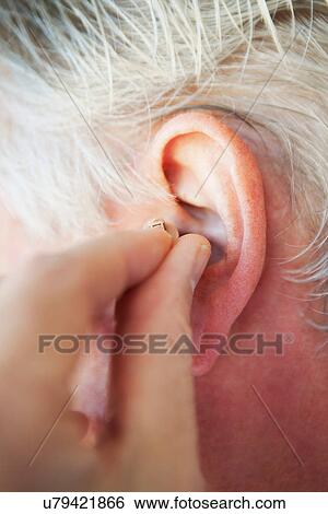 Older person inserting hearing aid View Large Photo Image Stock Photograph - Older person inserting hearing aid. Fotosearch