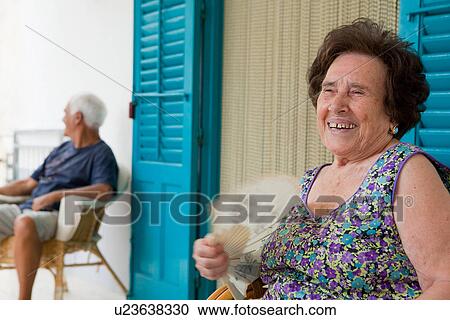 Stock Image - Older woman fanning herself outdoors. Fotosearch