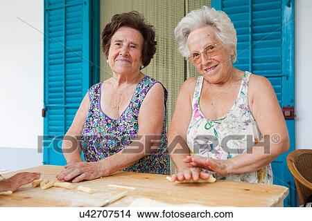Picture - Older women making pasta together. Fotosearch