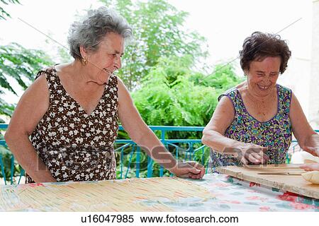 Older women making pasta together View Large Photo Image Stock Photography - Older women making pasta together. Fotosearch