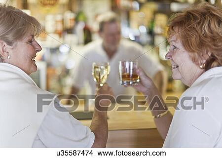 Older women toasting each other at bar View Large Photo Image Picture - Older women toasting each other at bar. Fotosearch