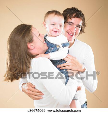 Stock Photo - Parents holding frowning toddler. Fotosearch