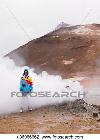 Stock Image - Photographer standing in steaming geyser. Fotosearch