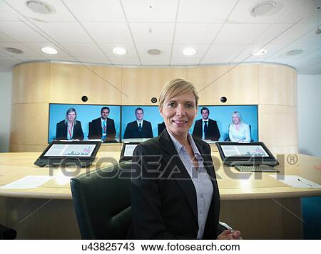 Portrait of businesswoman sitting in meeting room with colleagues on video conference screens View Large Photo Image Stock Image - Portrait of businesswoman sitting in meeting room with colleagues on video conference screens. Fotosearch