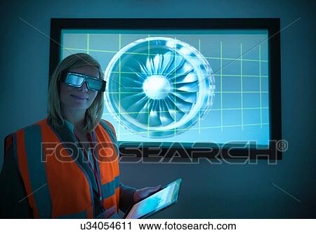 Stock Image - Portrait of engineer holding digital tablet and standing in front of engine part on 3D screen. Fotosearch