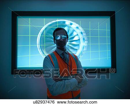 Stock Photograph - Portrait of engineer standing in front of engine part on 3D screen. Fotosearch