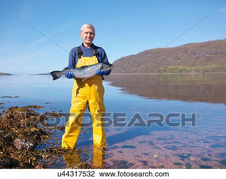 Portrait of fisherman standing in loch holding freshly caught salmon View Large Photo Image Stock Image - Portrait of fisherman standing in loch holding freshly caught salmon. Fotosearch