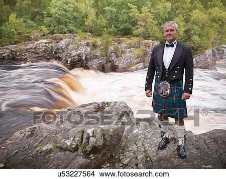 Portrait of man standing by flowing river in traditional Scottish Prince Charlie outfit with Douglas Modern Tartan View Large Photo Image Picture - Portrait of man standing by flowing river in traditional Scottish Prince Charlie outfit with Douglas Modern Tartan. Fotosearch