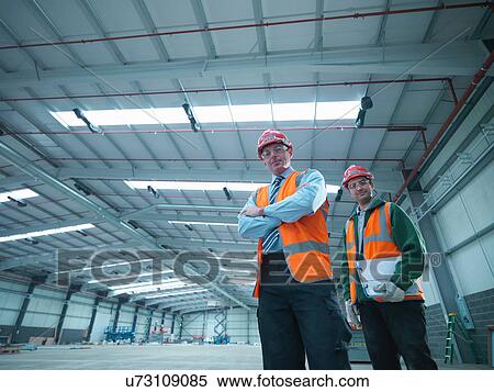 Stock Photography - Portrait of site foreman and apprentice in partly completed factory. Fotosearch
