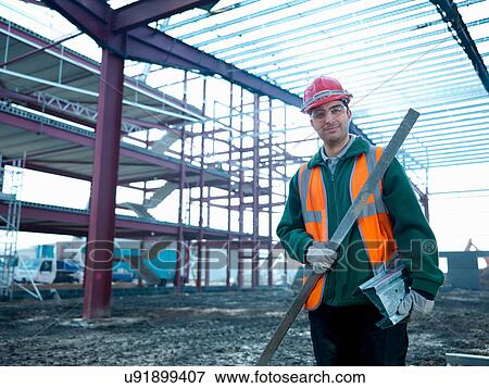 Stock Photo - Portrait of workman beneath steel construction frame on building site. Fotosearch