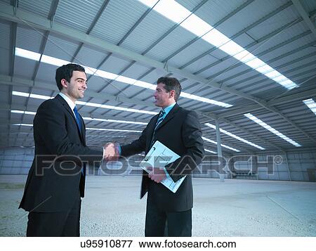 Stock Photo - Property managers shaking hands in finished factory building. Fotosearch