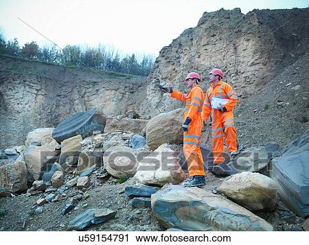 Quarrymen in discussion amid rocks and cliff face of quarry View Large Photo Image Stock Image - Quarrymen in discussion amid rocks and cliff face of quarry. Fotosearch