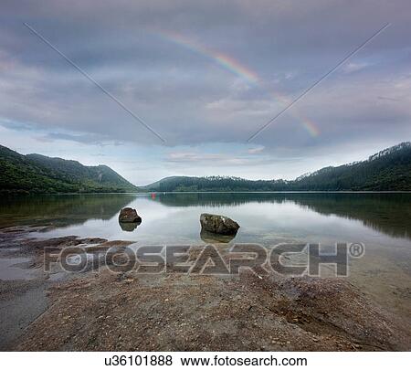 Rainbow stretching over rocky beach View Large Photo Image Stock Photo - Rainbow stretching over rocky beach. Fotosearch