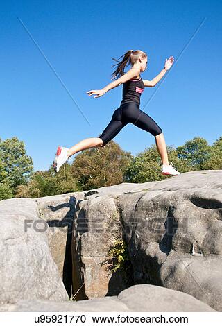 Stock Image - Rock climber jumping between rocks. Fotosearch
