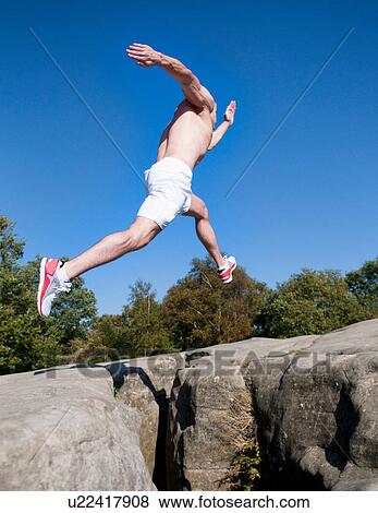 Rock climber jumping between rocks View Large Photo Image Stock Photo - Rock climber jumping between rocks. Fotosearch