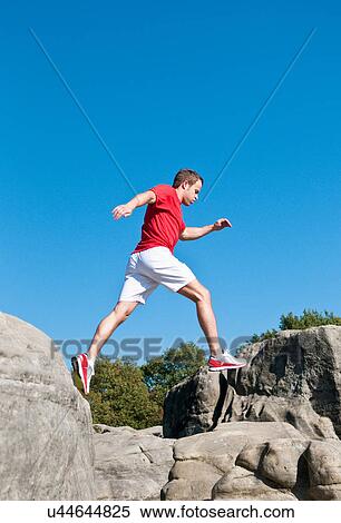 Rock climber jumping between rocks View Large Photo Image Stock Photography - Rock climber jumping between rocks. Fotosearch
