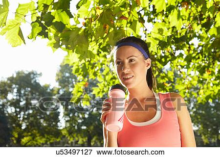 Stock Photo - Runner drinking water in park. Fotosearch