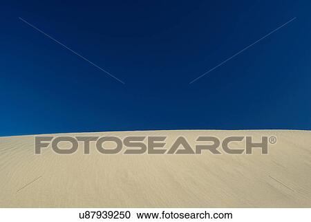 Sand dune under blue sky View Large Photo Image Stock Image - Sand dune under blue sky. Fotosearch