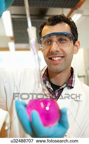 Stock Photo - Scientist examining liquid in beaker. Fotosearch
