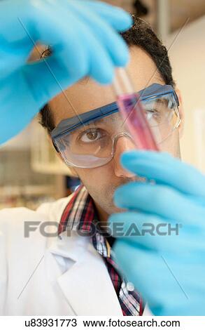 Stock Image - Scientist examining liquid in test tube. Fotosearch