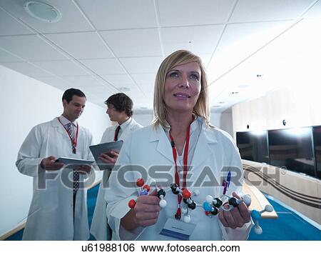 Stock Photograph - Scientist in laboratory with colleagues and holding molecular model. Fotosearch