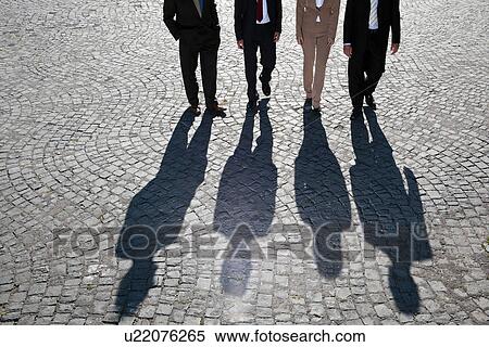 Stock Photography - Shadows walking on cobbled road. Fotosearch