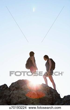 Picture - Silhouette of hikers standing on rock. Fotosearch