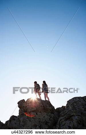 Silhouette of hikers standing on rock View Large Photo Image Stock Photograph - Silhouette of hikers standing on rock. Fotosearch
