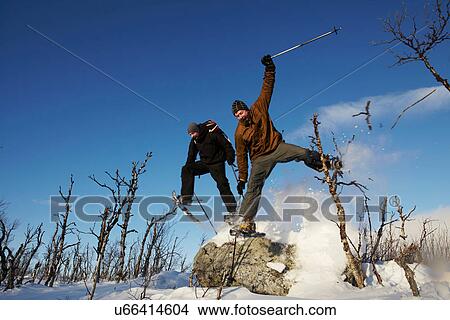 Skiers jumping off rock in snow View Large Photo Image Picture - Skiers jumping off rock in snow. Fotosearch