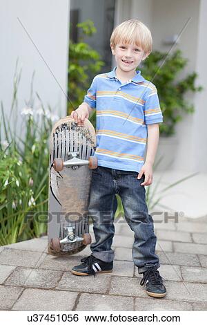 Smiling boy carrying skateboard View Large Photo Image Stock Photograph - Smiling boy carrying skateboard. Fotosearch