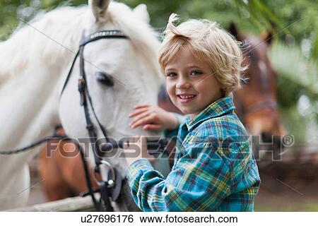Smiling boy petting horse in yard View Large Photo Image Stock Photograph - Smiling boy petting horse in yard. Fotosearch